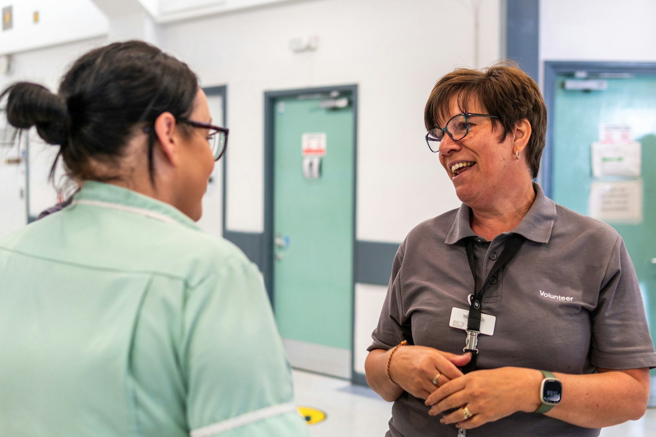 Two colleagues sharing a laugh in a hospital hallway
